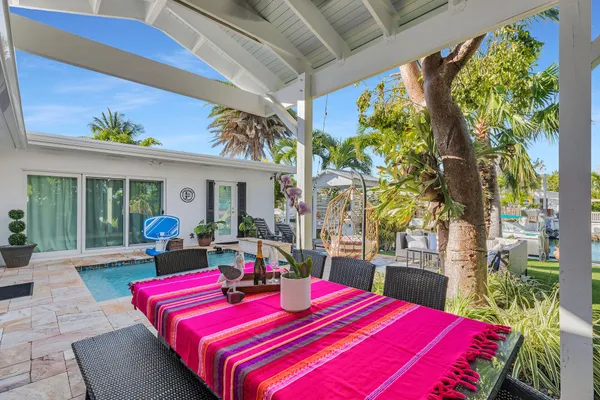 a patio with a table and chairs and potted plants
