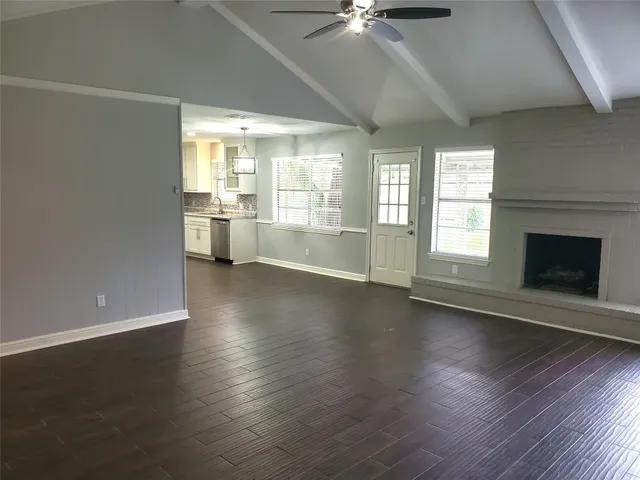 an empty room with wooden floor fireplace and windows