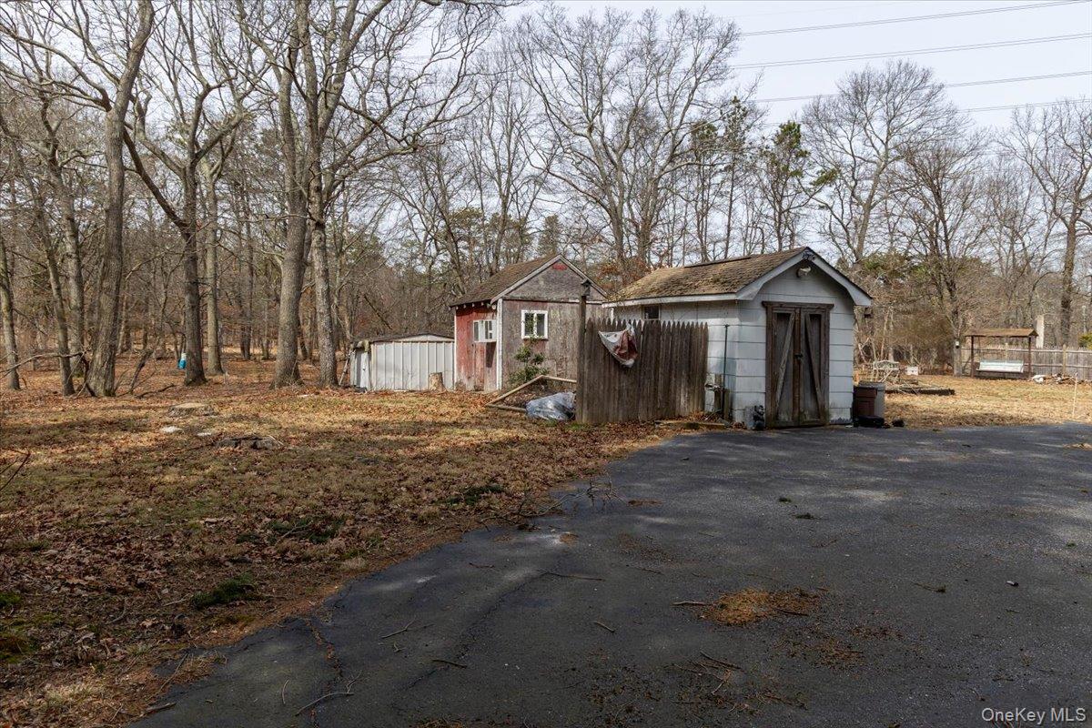 309 Primrose Path Manorville, NY 11949 - Photo 5 of 26 a front view of a house with a dirt yard and a large tree