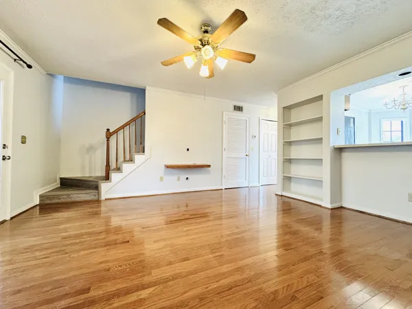 a view of an empty room with a window and wooden floor