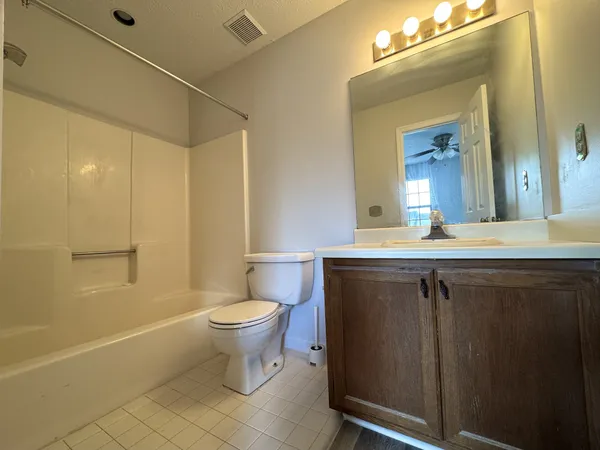 a bathroom with a granite countertop sink a toilet a mirror and shower