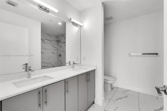 a bathroom with a double vanity sink toilet and mirror