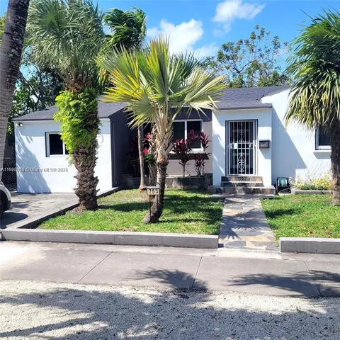 a front view of a house with a yard and potted plants