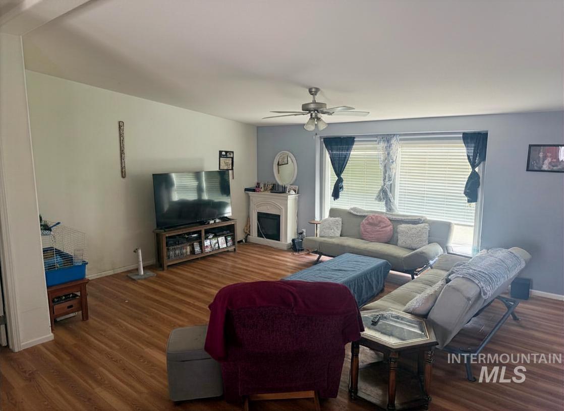 100 Ellsworth Street Vale, OR 97918 - Photo 3 of 25 Spacious living area featuring wood-finish flooring, a ceiling fan with integrated lighting, and a prominent window with horizontal blinds