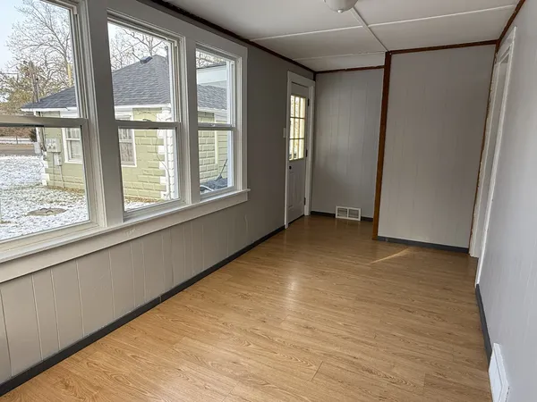 a view of an empty room with a window and wooden floor