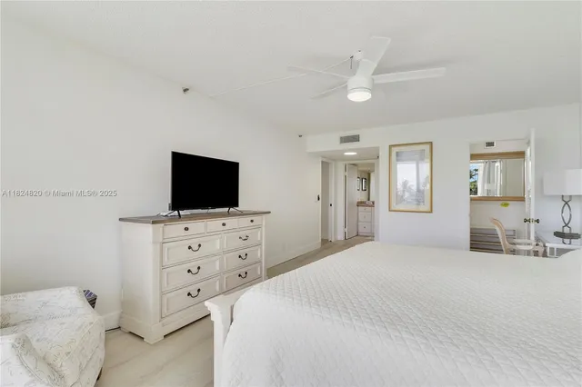 a bedroom with a bed and a flat screen tv in white walls