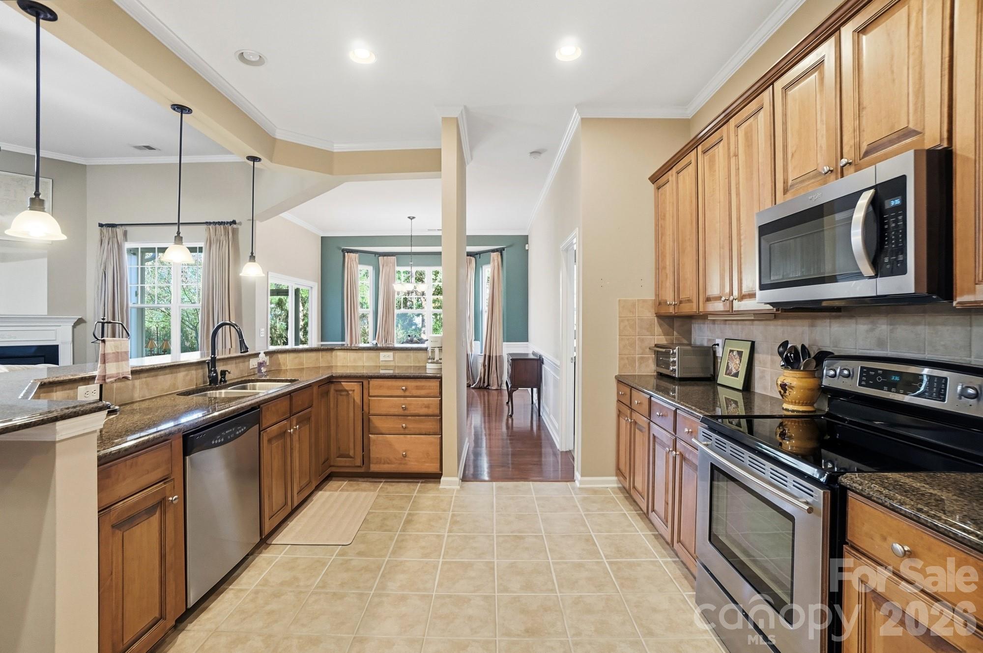 425 Silver Cypress Lane Fort Mill, SC 29708 - Photo 11 of 40 a large kitchen with stainless steel appliances granite countertop a stove top oven a sink dishwasher a refrigerator and cabinets with wooden floor