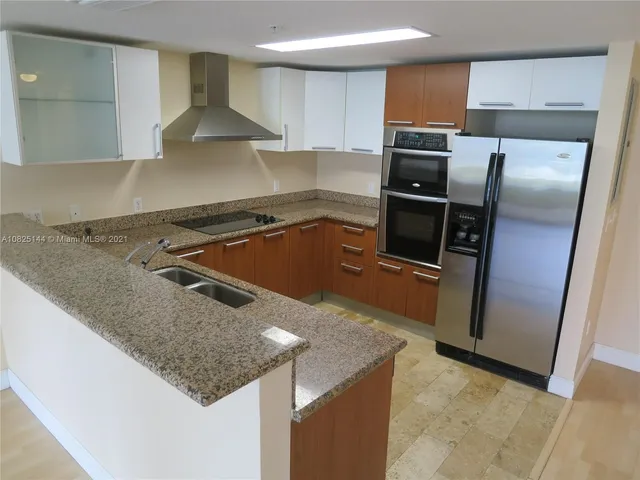 a kitchen with stainless steel appliances granite countertop a refrigerator and a stove top oven