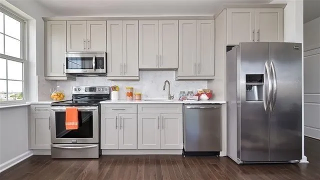 a kitchen with stainless steel appliances granite countertop a refrigerator sink and white cabinets