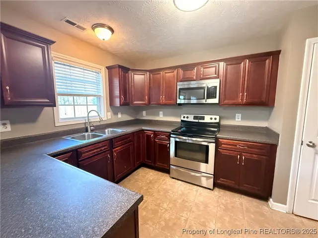 a kitchen with granite countertop a stove top oven sink and cabinets