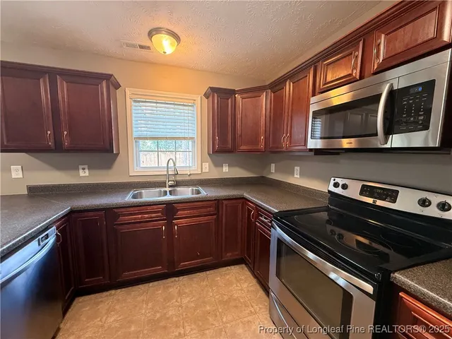 a kitchen with stainless steel appliances granite countertop a stove a sink and a microwave