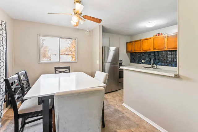 a kitchen with stainless steel appliances a stove a refrigerator a sink with a dining table and chair