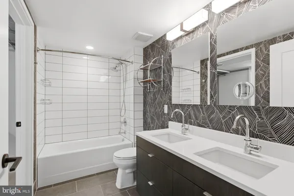a bathroom with a bathtub shower sink vanity mirror and toilet