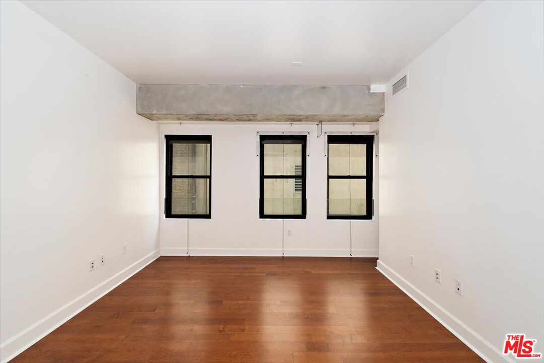 416 South Spring Street, Unit 609 Los Angeles, CA 90013 - Photo 16 of 24 an empty room with wooden floor and windows