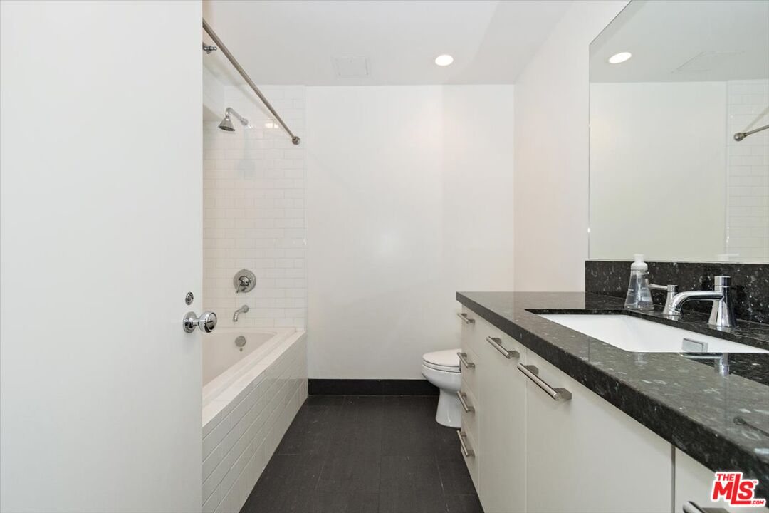 416 South Spring Street, Unit 609 Los Angeles, CA 90013 - Photo 22 of 24 a bathroom with a granite countertop sink a toilet and shower