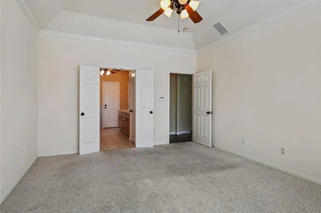 an empty room with a chandelier fan and closet