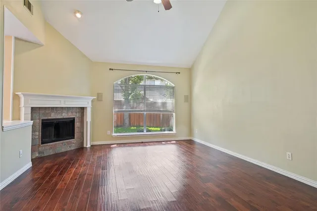 an empty room with wooden floor fireplace and windows