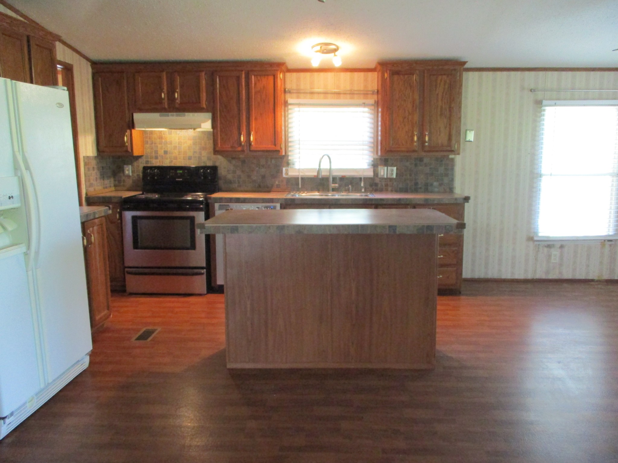 2080 North Commerce Road Lebanon, TN 37090 - Photo 5 of 40 a kitchen with granite countertop wooden floors a stove and a refrigerator
