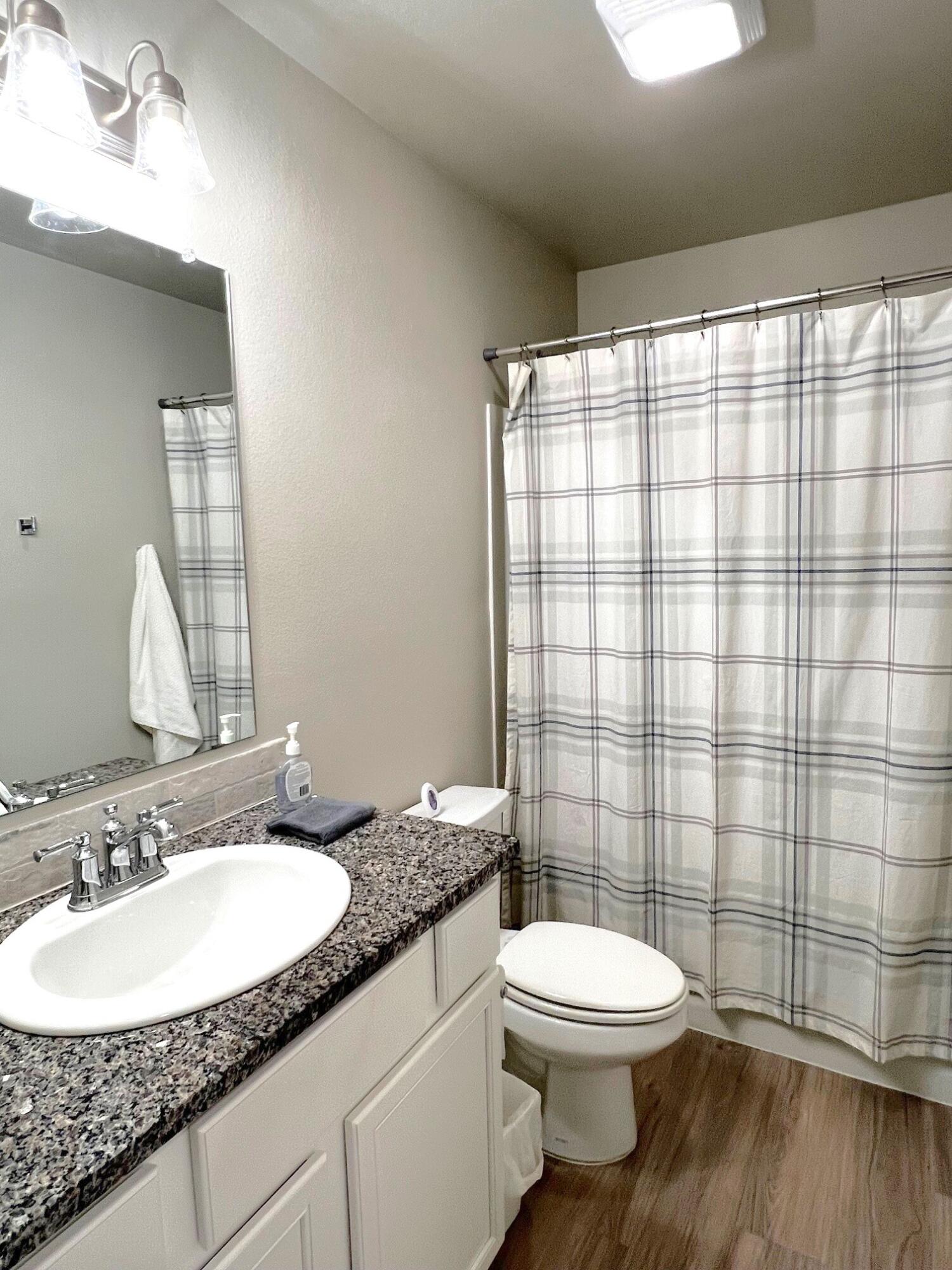 2006 135th Street Lubbock, TX 79423 - Photo 22 of 24 a bathroom with a granite countertop toilet a sink and a mirror