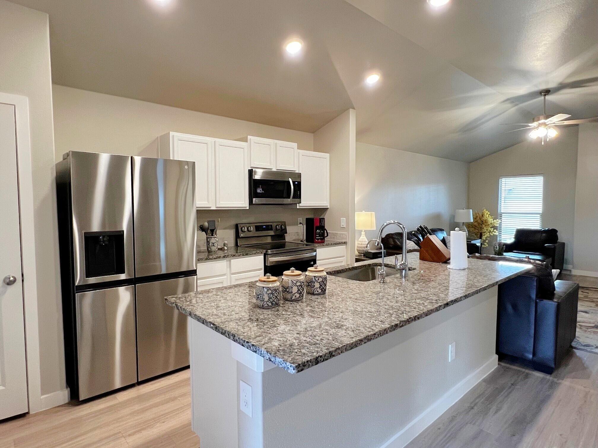 2006 135th Street Lubbock, TX 79423 - Photo 6 of 24 a kitchen with stainless steel appliances granite countertop a refrigerator a sink a stove a microwave and wooden floor