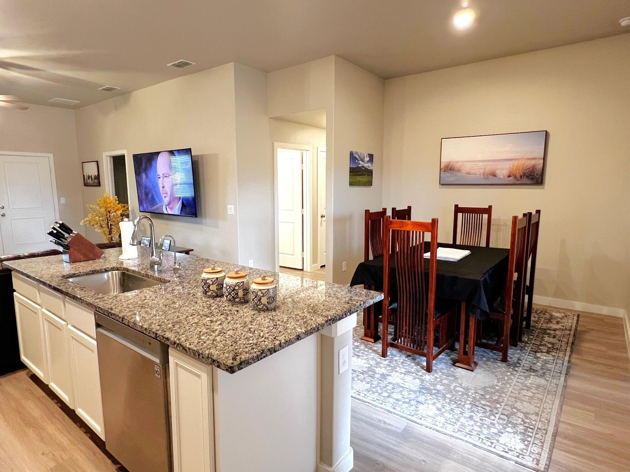 2006 135th Street Lubbock, TX 79423 - Photo 7 of 24 a view of kitchen island with granite countertop dining table chairs cabinets and wooden floor