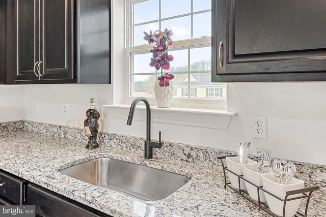 a kitchen with a granite countertop sink and natural light