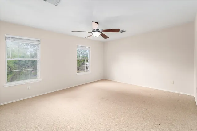 an empty room with windows and ceiling fan