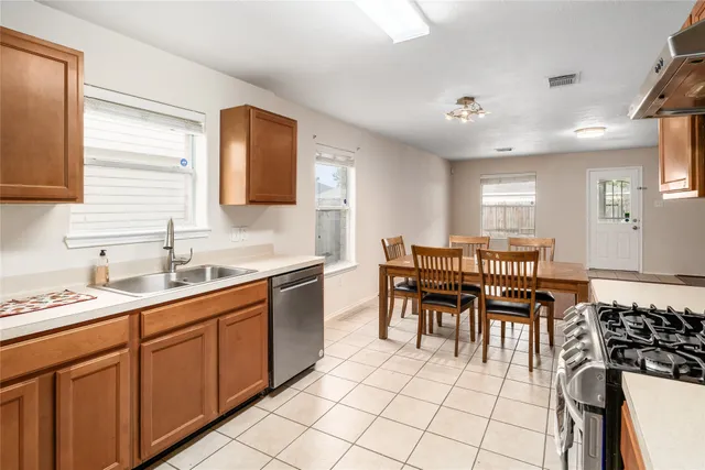 a kitchen with stainless steel appliances granite countertop a sink a stove a dining table and chairs
