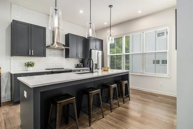 a kitchen with stainless steel appliances granite countertop a sink a stove a refrigerator and island with wooden floor