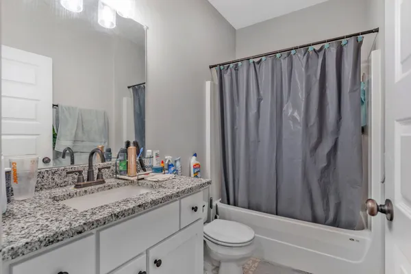 a bathroom with a granite countertop sink toilet and mirror