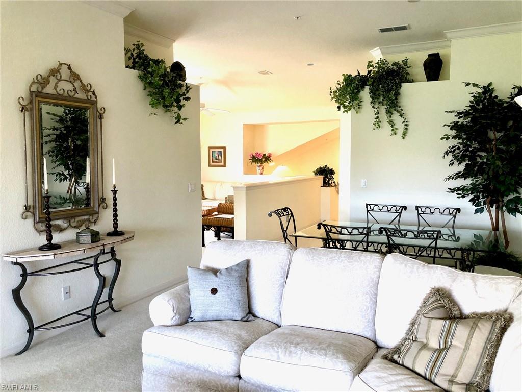 6879 Redbay Park Road, Unit 203 Naples, FL 34109 - Photo 11 of 34 a living room with furniture a chandelier and a mirror