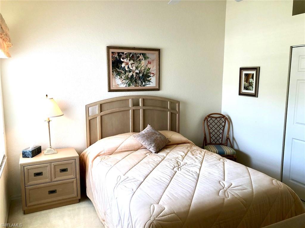 6879 Redbay Park Road, Unit 203 Naples, FL 34109 - Photo 14 of 34 a bedroom with a bed and a lamp on dresser