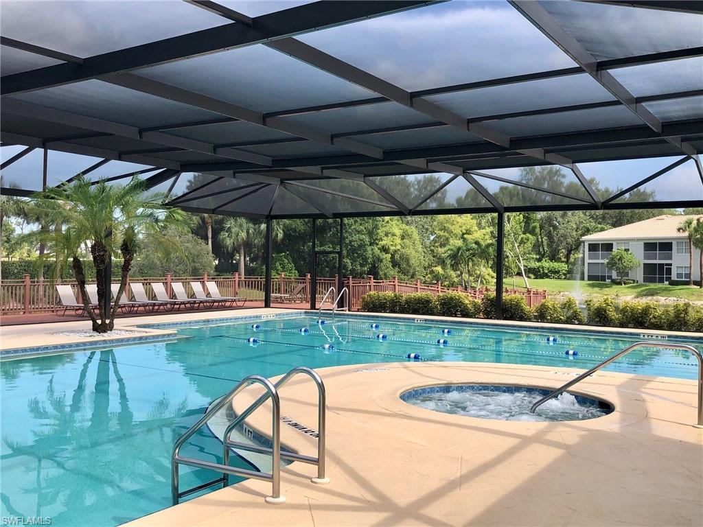 6879 Redbay Park Road, Unit 203 Naples, FL 34109 - Photo 30 of 34 a view of a backyard with table and chairs under an umbrella