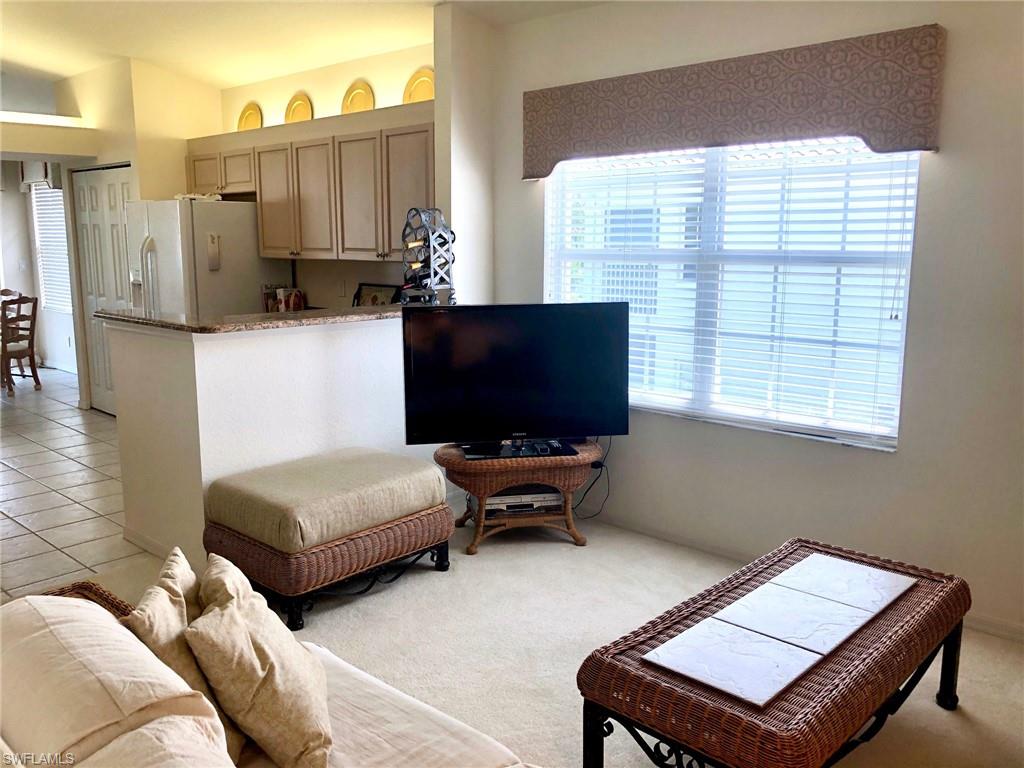 6879 Redbay Park Road, Unit 203 Naples, FL 34109 - Photo 8 of 34 a living room with furniture a flat screen tv and a window