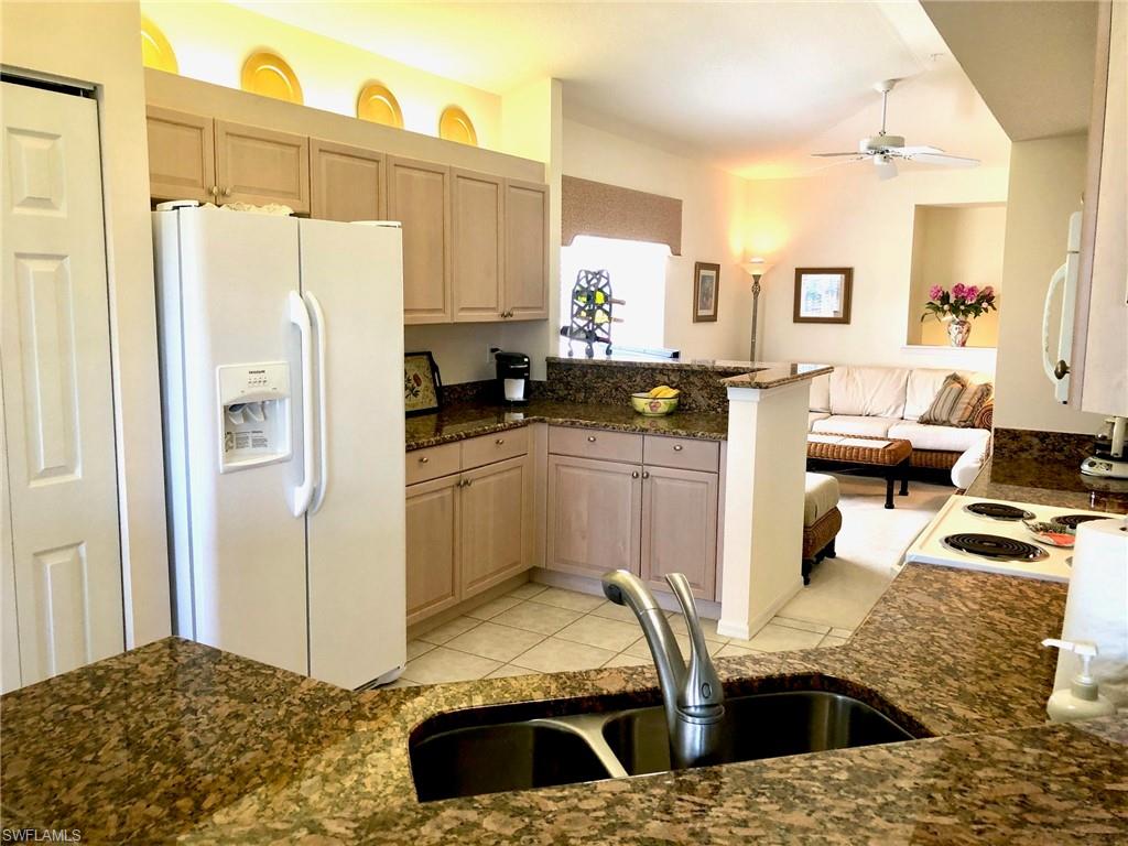 6879 Redbay Park Road, Unit 203 Naples, FL 34109 - Photo 9 of 34 a kitchen with stainless steel appliances kitchen island granite countertop a refrigerator and a stove
