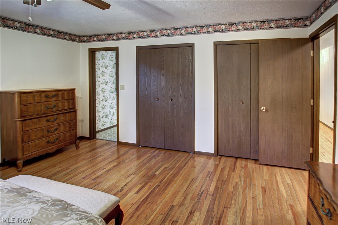6013 Rousseau Drive Parma, OH 44129 - Photo 22 of 50 Master bedroom with ceiling fan, a textured ceiling, light wood-type flooring, and multiple closets