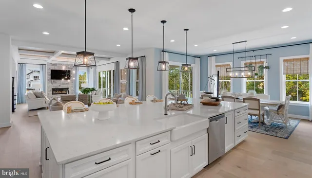 an open kitchen with stainless steel appliances granite countertop a stove a sink a oven and a dining table with white cabinets