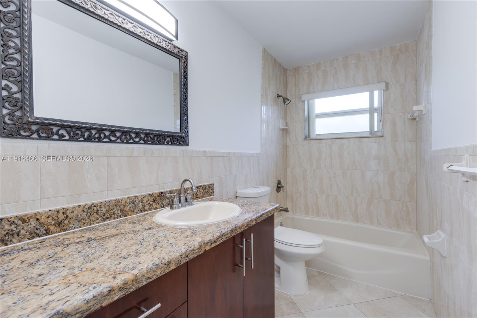 5425 Madison Street Hollywood, FL 33021 - Photo 15 of 45 a bathroom with a granite countertop sink a toilet and a mirror