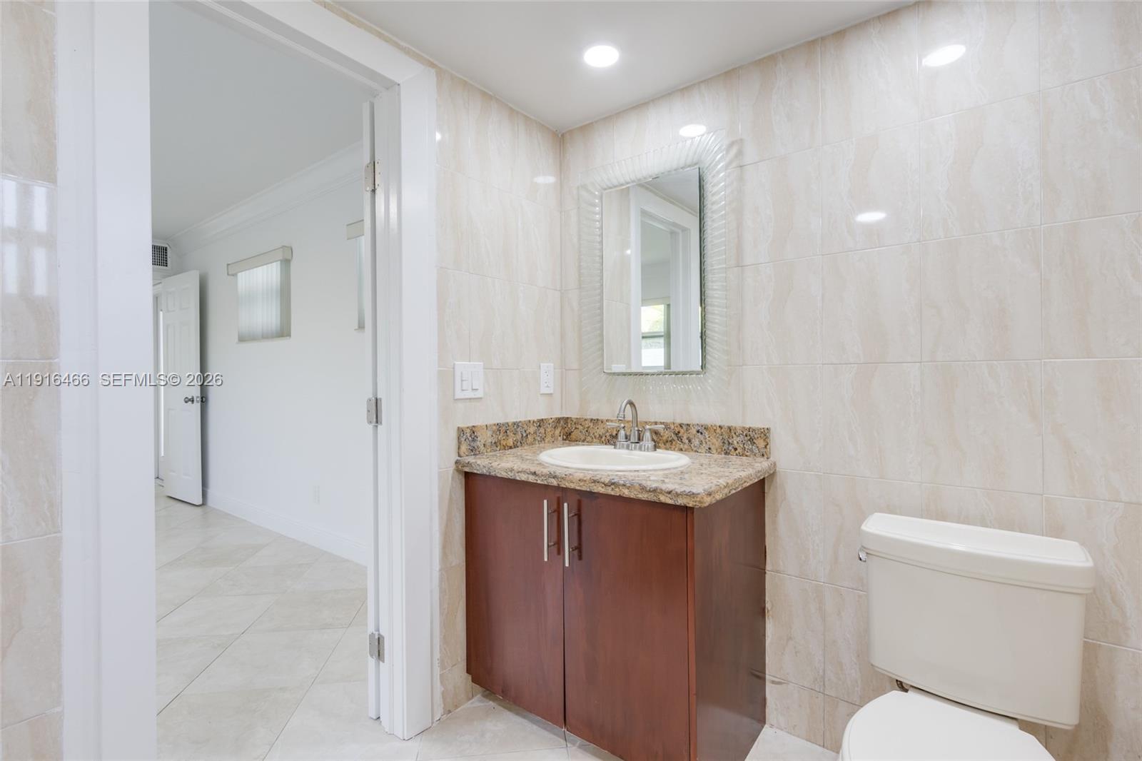 5425 Madison Street Hollywood, FL 33021 - Photo 24 of 45 a bathroom with a granite countertop sink a toilet and a mirror