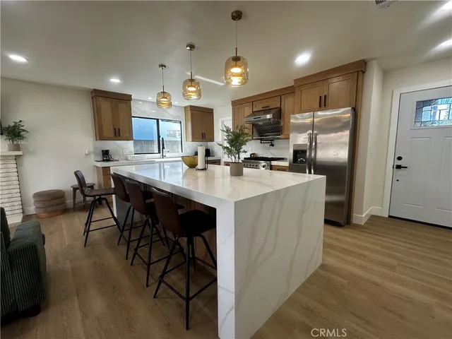 a kitchen with stainless steel appliances kitchen island granite countertop a table chairs sink and cabinets