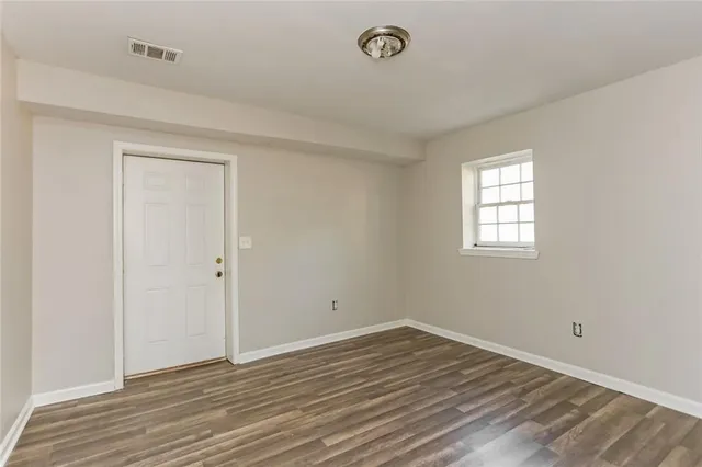an empty room with wooden floor and windows