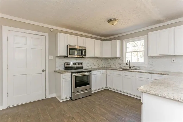 a kitchen with granite countertop white cabinets and appliances