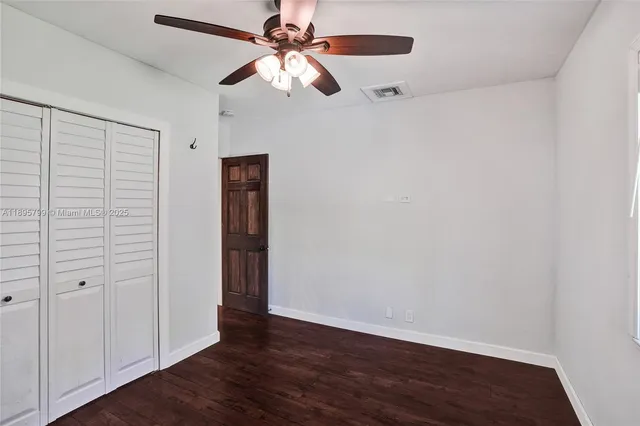 an empty room with wooden floor chandelier fan and closet