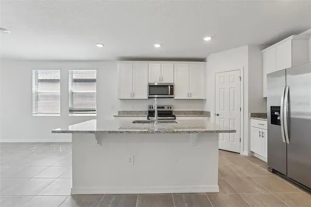 a kitchen with stainless steel appliances granite countertop a stove a sink and a refrigerator