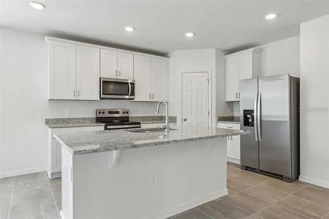 a kitchen with stainless steel appliances granite countertop a refrigerator a stove a sink and a microwave