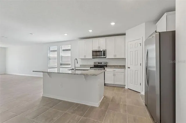 a kitchen with stainless steel appliances granite countertop a refrigerator and a stove top oven