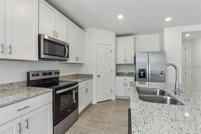 a kitchen with stainless steel appliances granite countertop a sink a stove top oven and refrigerator
