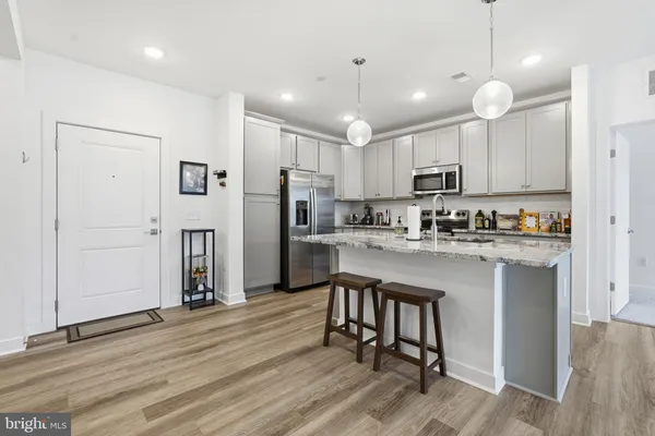 a kitchen with kitchen island a refrigerator a stove a sink and white cabinets with wooden floor