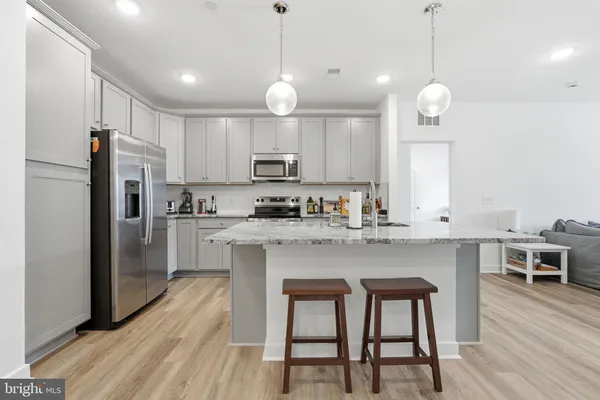 a kitchen with kitchen island granite countertop a sink a center island a counter space stainless steel appliances and cabinets