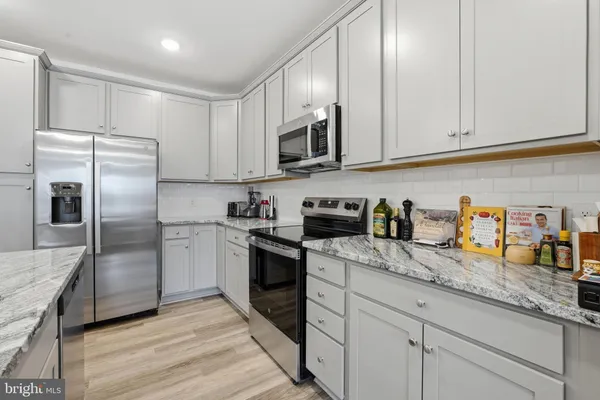 a kitchen with granite countertop white cabinets stainless steel appliances and a sink